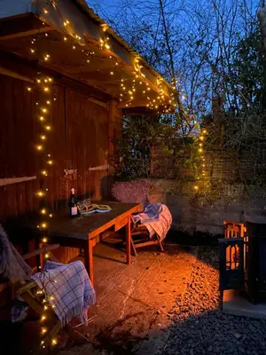 a patio with a wooden table and string lights at The Pig and Sty in Hereford