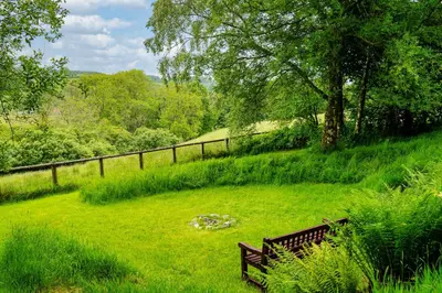a park bench sitting in the grass in a field at Brynarth Country Cottages in Aberystwyth