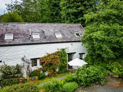 a white house with an umbrella in a garden at Brynarth Country Cottages in Aberystwyth