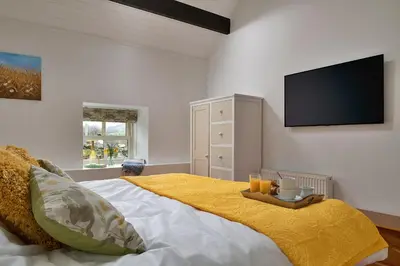a bedroom with a large bed with a flat screen tv at Finest Retreats - Moelis Granary - Luxury Cottage with Hot Tub in Llandrillo