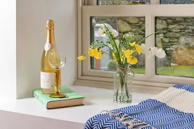 a bottle of champagne and a vase of flowers on a table at Finest Retreats - Moelis Granary - Luxury Cottage with Hot Tub in Llandrillo