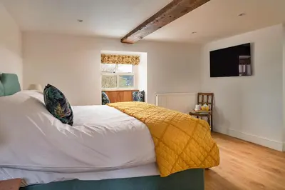 a bedroom with a bed with a yellow blanket on it at Finest Retreats - Moelis Granary - Luxury Cottage with Hot Tub in Llandrillo