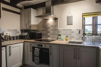 a kitchen with white cabinets and a sink at River Cottage, Melverley in Melverley