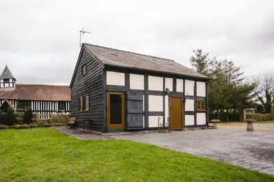 a small black and white building with yellow doors at River Cottage, Melverley in Melverley