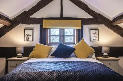 a bedroom with a bed with blue and yellow pillows at River Cottage, Melverley in Melverley