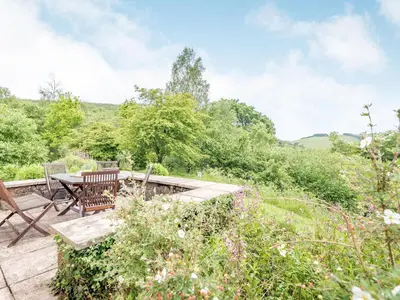 a patio with a table and chairs in a garden at Cwmfron House in Llanidloes