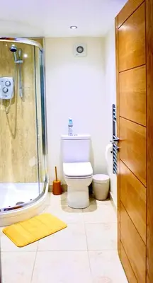 a bathroom with a toilet and a glass shower at “Dragons Den” Centrally located Modern Apartment in Aberystwyth