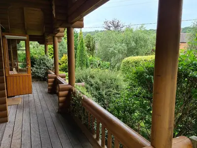 a porch of a wooden house with bushes and trees at Countryside Log Cabin With Hot Tub - Beech in Leominster