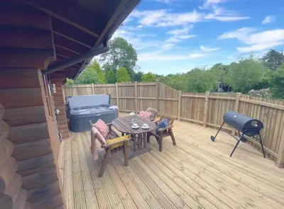 two children sleeping on a deck with a table and a grill at Countryside Log Cabin With Hot Tub - Beech in Leominster