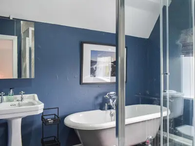 a blue bathroom with a tub and a sink and a shower at Crogen Gatehouse Lodge in Corwen