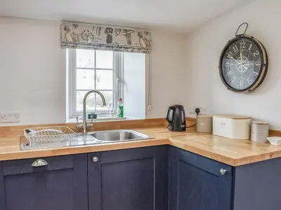 a kitchen with a sink and a clock on the wall at Crogen Gatehouse Lodge in Corwen