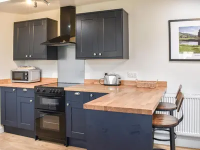a kitchen with black cabinets and a wooden counter top at Crogen Gatehouse Lodge in Corwen
