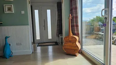 a wooden guitar sitting in a room next to a door at Talarfor Barmouth in Barmouth
