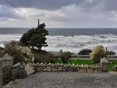 a stone fence with the ocean in the background at Talarfor Barmouth in Barmouth