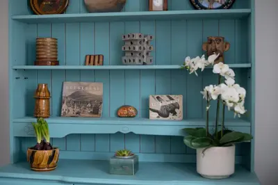 a blue shelf with a vase of flowers and plates at Cottage in heart of Dolgellau with parking in Dolgellau
