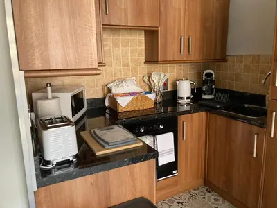 a kitchen with wooden cabinets and a counter with a microwave at Rooftops - bijou sister apartment to Assembly View - free parking permit provided in Ludlow