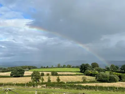 a rainbow in the sky over a field at Hay View Lodges - Barn End in Hay-on-Wye