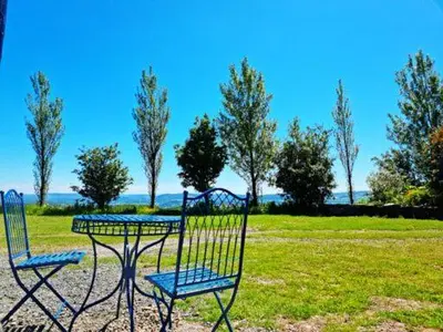 two chairs and a table in a field with trees at Pen Bryn Shepherd Hut in Hay-on-Wye