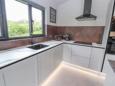 a white kitchen with a sink and a window at Pool View in Meifod