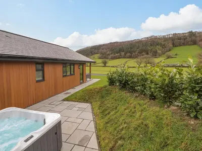 a hot tub in a yard next to a house at Pool View in Meifod
