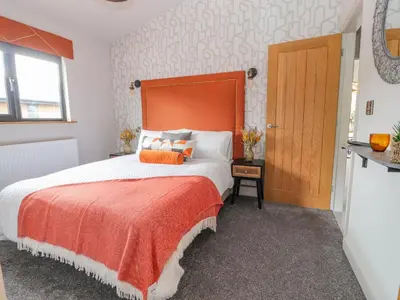 a bedroom with a large bed with an orange headboard at Pool View in Meifod