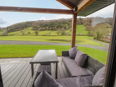 a couch on a deck with a view of a field at Pool View in Meifod