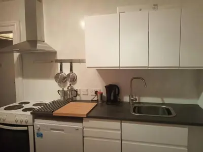 a kitchen with white cabinets and a sink and a stove at Apartment One Aberystwyth Town Centre in Aberystwyth