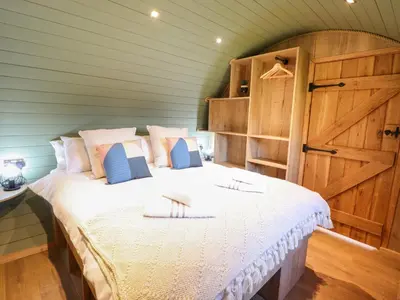 a bedroom with a large bed with a wooden door at Nant yr Esgair in Machynlleth