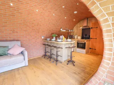 a living room with a brick wall and a kitchen at Nant yr Esgair in Machynlleth