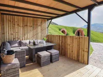 a patio with a couch and a table on a wooden deck at Nant yr Esgair in Machynlleth
