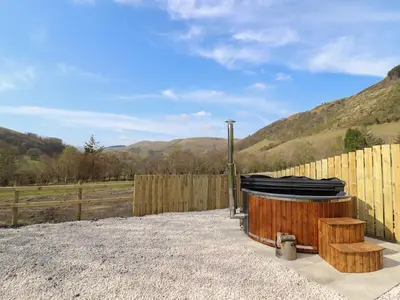 a hot tub sitting next to a wooden fence at Nant yr Esgair in Machynlleth