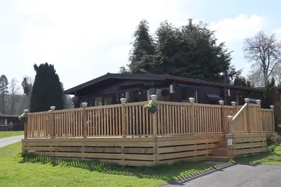 a wooden fence in front of a house at HEDDFAN, Luxury 3 bedroom timber lodge, Now with WiFi, Caer Beris Holiday Park, Builth Wells, SORRY NO TRADESMEN OR CONTRACTORS ALLOWED in Builth Wells