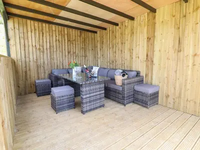 a patio with a table and chairs in a wooden wall at Nant y Garnedd in Machynlleth