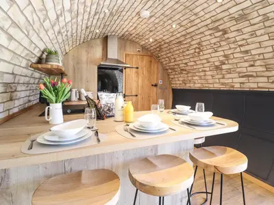 a kitchen with a table with chairs and a fireplace at Nant y Garnedd in Machynlleth