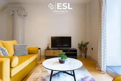 a living room with a yellow couch and a table at Dashing 2 Bedroom Duplex Apartment, Free Parking in Shrewsbury