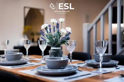 a wooden table with glasses and a vase of flowers at Dashing 2 Bedroom Duplex Apartment, Free Parking in Shrewsbury