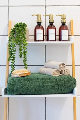 a shelf with three bottles of soap and towels at Bridge Hideaway in Llangollen
