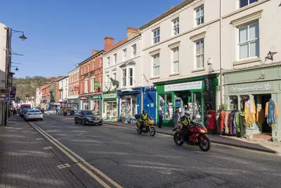 two people are riding motorcycles down a city street at Bridge Hideaway in Llangollen