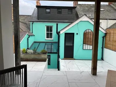 a blue house with a courtyard in front of it at Swn Y Don New Quay in New Quay