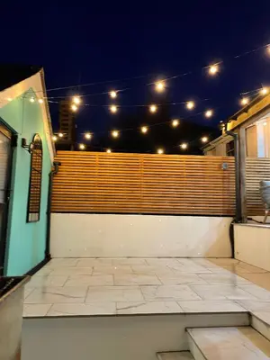 a patio with lights on a fence at night at Swn Y Don New Quay in New Quay