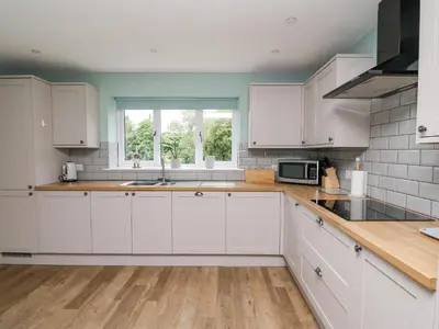 a kitchen with white cabinets and a window at Talarddu Cottage in Builth Wells