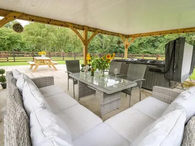 a patio with a table and chairs and a grill at Talarddu Cottage in Builth Wells