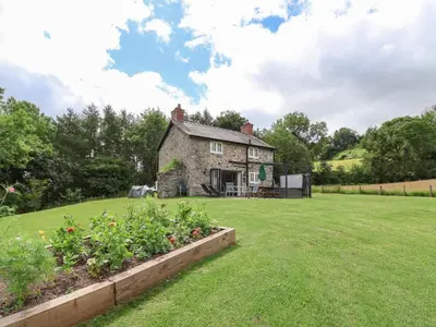 an old stone house in the middle of a yard at Cae Iocyn in Wrexham