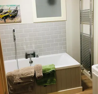a bathroom with a bath tub with green towels at The Art Attic a Stylish Boutique Apartment in Builth Wells