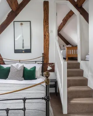 a bedroom with a bed with green pillows and a staircase at The Old Fire Station Ludlow in Ludlow