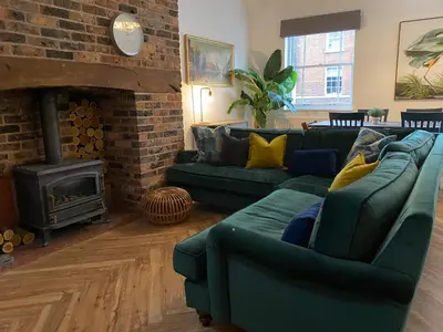 a living room with two green couches and a fireplace at The Old Fire Station Ludlow in Ludlow