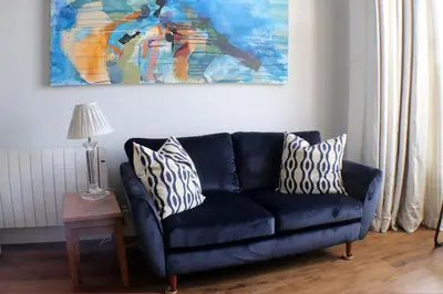 a blue couch in a living room with a painting at Seaside Apartment in Aberystwyth