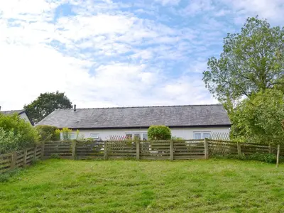 a white house behind a wooden fence at Blackbird Cottage in Llanfair Caereinion