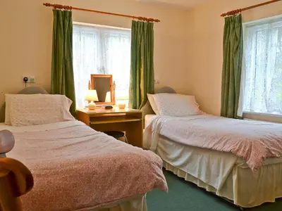 two beds in a room with green curtains at Blackbird Cottage in Llanfair Caereinion