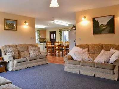 a living room with two couches and a kitchen at Swallow Cottage in Llanfair Caereinion